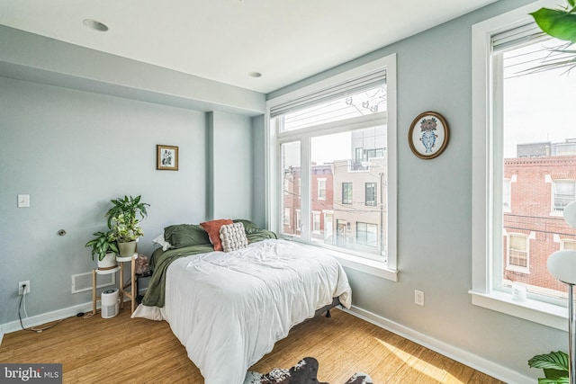 bedroom with baseboards, visible vents, and wood finished floors
