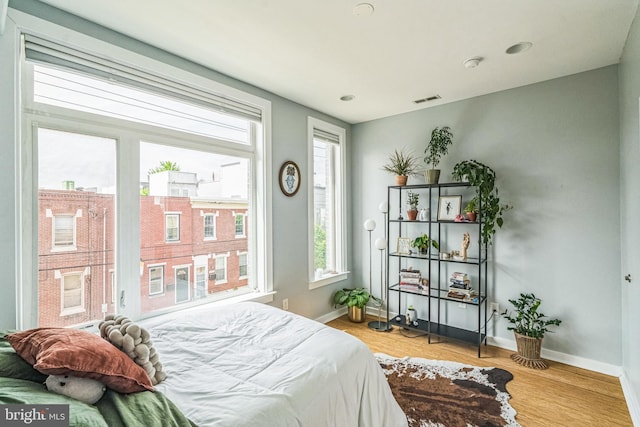 bedroom featuring baseboards, light wood finished floors, and visible vents