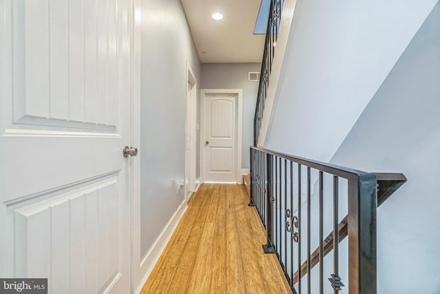 corridor featuring visible vents, baseboards, light wood finished floors, an upstairs landing, and recessed lighting