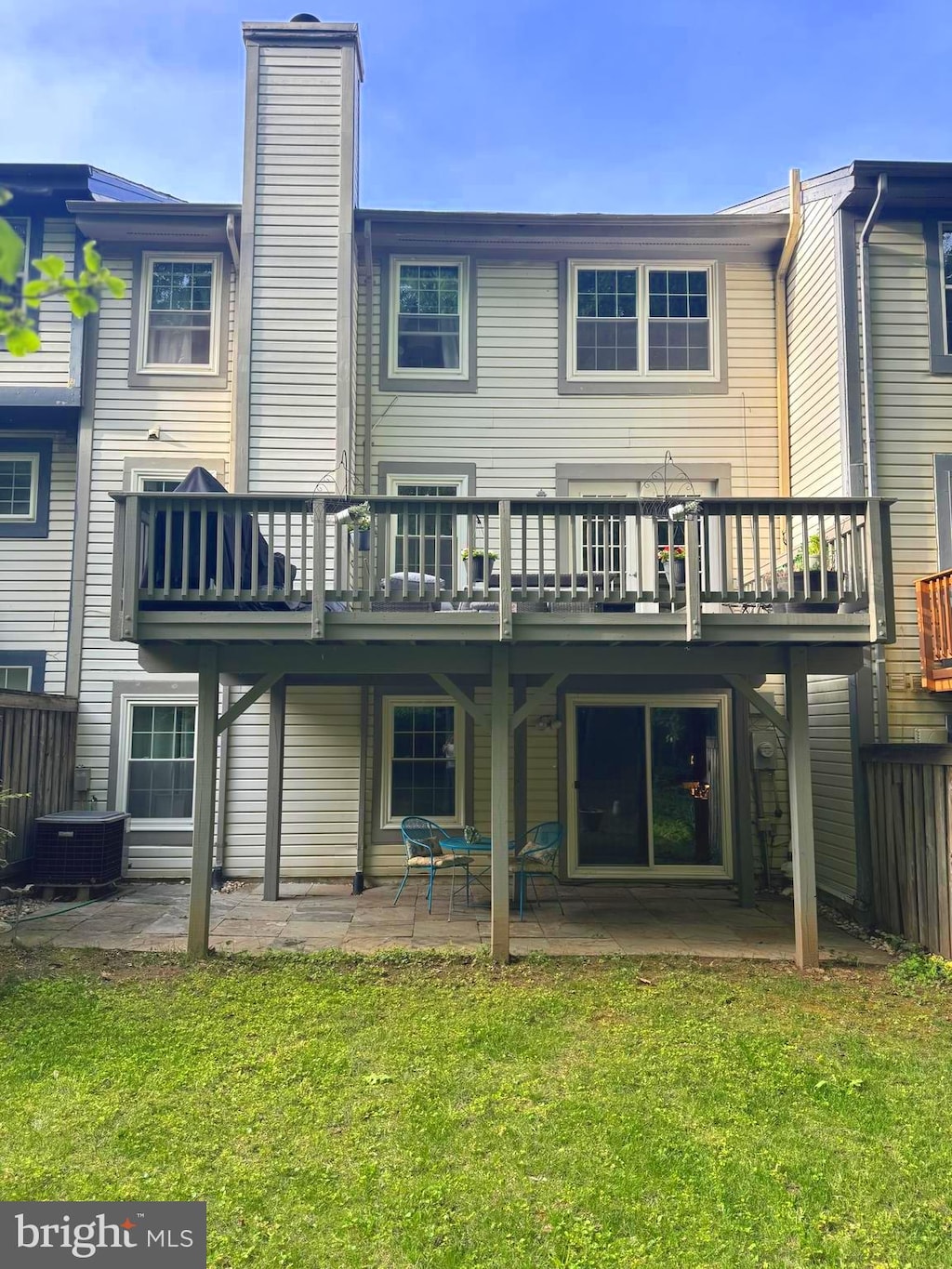back of house featuring a wooden deck, a chimney, cooling unit, a patio area, and a yard