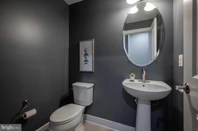 bathroom with baseboards, tile patterned flooring, and toilet