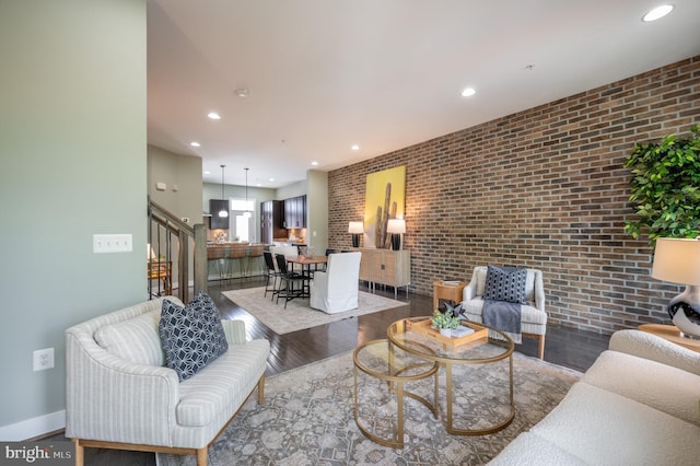 living room with recessed lighting, wood finished floors, brick wall, and stairway