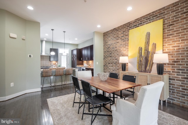 dining area featuring recessed lighting, baseboards, dark wood-style floors, and brick wall