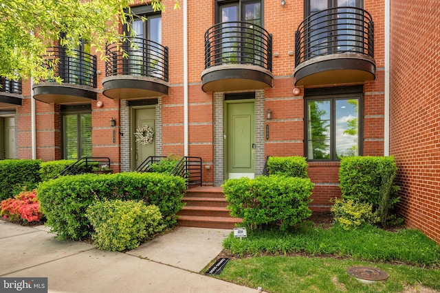 entrance to property featuring brick siding and a balcony