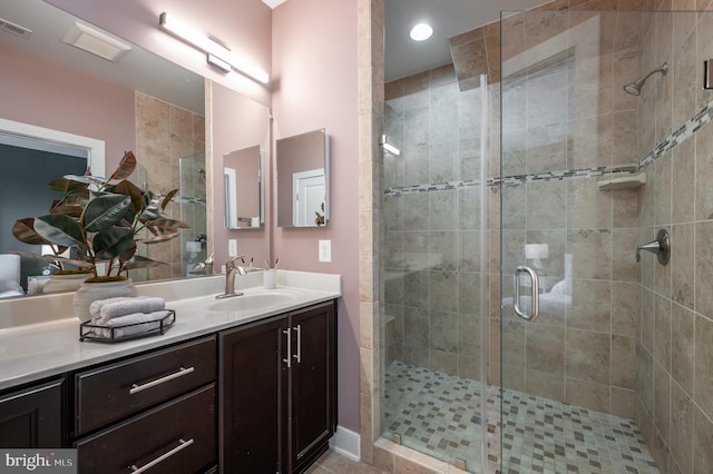 full bath with vanity, a shower stall, and visible vents
