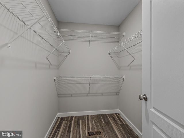 walk in closet with dark wood finished floors and visible vents