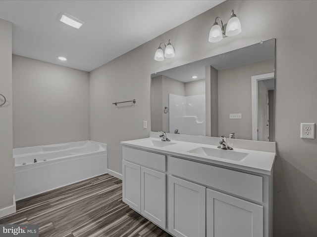 bathroom featuring double vanity, a sink, a bath, and wood finished floors