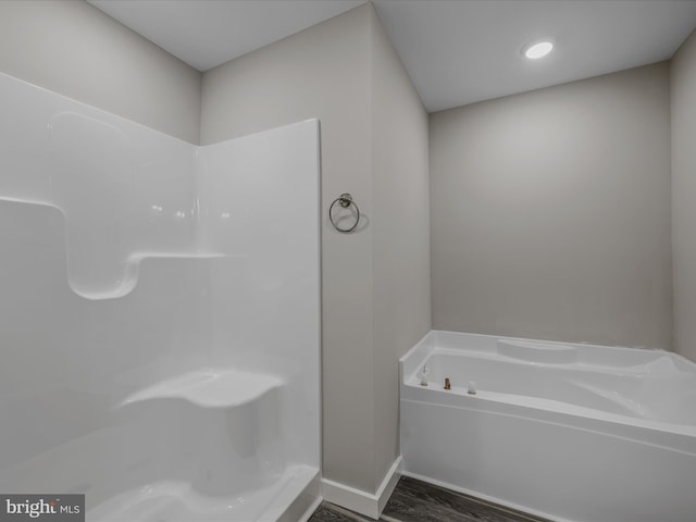 bathroom featuring walk in shower, baseboards, a garden tub, and wood finished floors