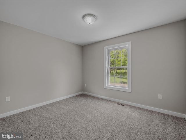 empty room featuring baseboards, visible vents, and carpet
