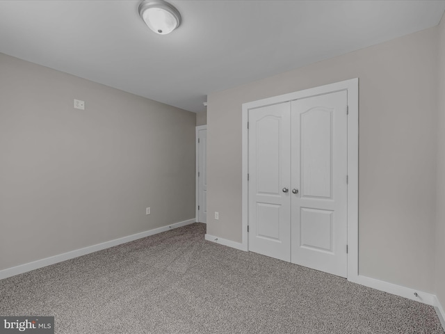 unfurnished bedroom featuring carpet flooring, baseboards, and a closet