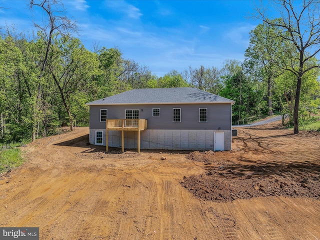 rear view of house featuring a shingled roof and a deck