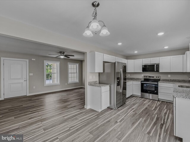 kitchen with light wood-style floors, baseboards, white cabinets, light stone counters, and stainless steel appliances