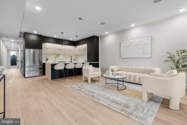 living room with recessed lighting, crown molding, light wood-type flooring, and visible vents