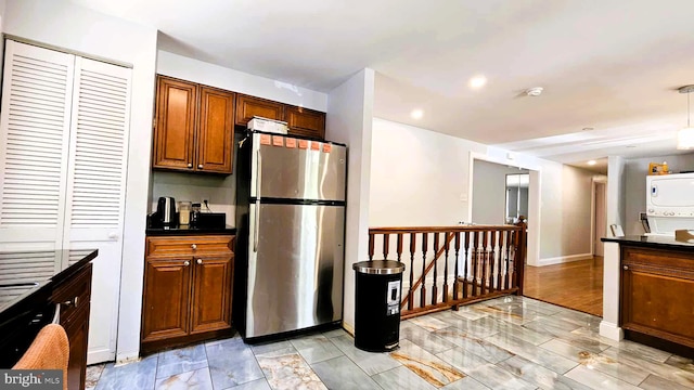 kitchen with dark countertops, freestanding refrigerator, brown cabinets, and marble finish floor
