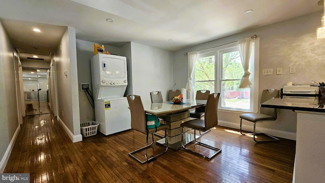 dining room with baseboards, stacked washing maching and dryer, and hardwood / wood-style floors