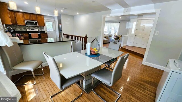 dining room featuring baseboards, recessed lighting, washer / dryer, and hardwood / wood-style flooring