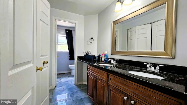 full bath featuring a sink, baseboards, toilet, and double vanity