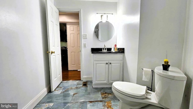 bathroom featuring vanity, marble finish floor, baseboards, and toilet