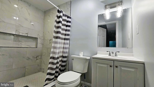full bath with vanity, a tile shower, and toilet