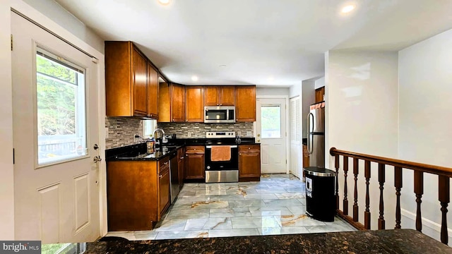 kitchen with decorative backsplash, marble finish floor, a wealth of natural light, and stainless steel appliances