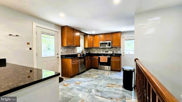 kitchen with brown cabinets, backsplash, a wealth of natural light, and stainless steel appliances