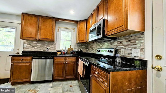 kitchen featuring backsplash, stainless steel appliances, brown cabinets, and a sink