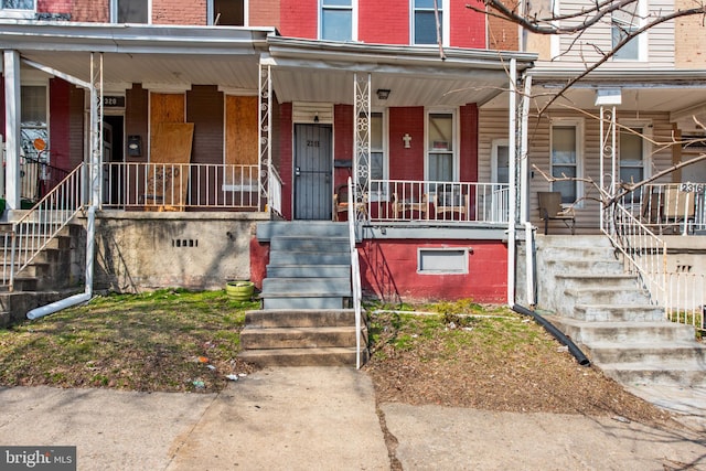 view of exterior entry featuring covered porch, crawl space, and brick siding