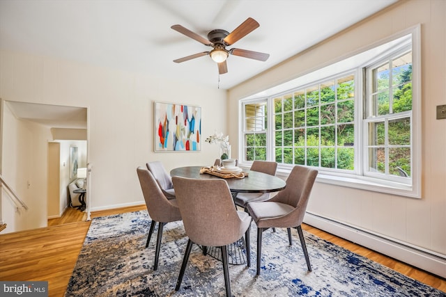 dining space with a baseboard heating unit, light wood-style floors, and a ceiling fan