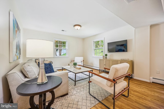 living room featuring light wood-type flooring, baseboards, a baseboard heating unit, and baseboard heating