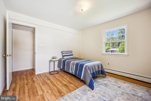 bedroom featuring light wood finished floors and a baseboard radiator