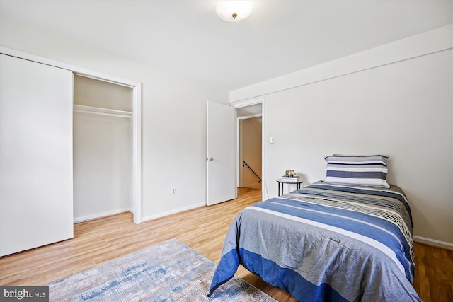 bedroom featuring wood finished floors, a closet, and baseboards