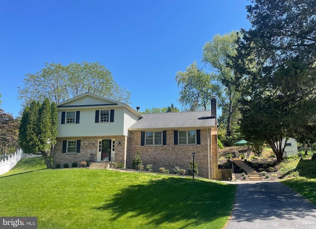 tri-level home featuring brick siding, a chimney, and stairs