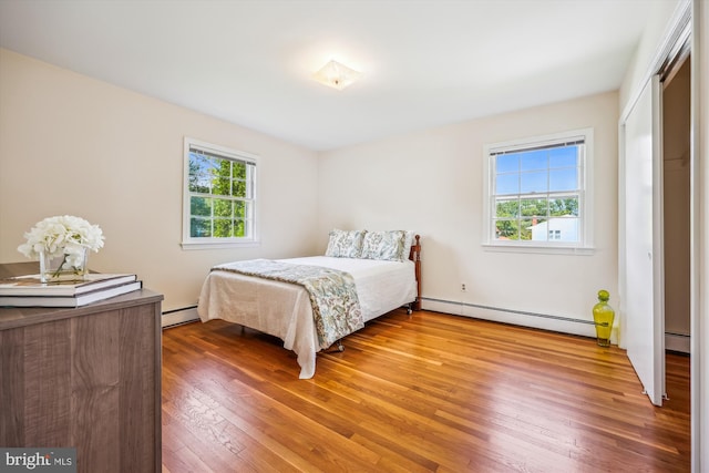 bedroom with a baseboard radiator and wood finished floors