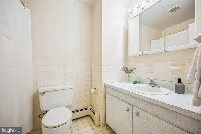 bathroom featuring a baseboard heating unit, tile walls, a wainscoted wall, toilet, and vanity