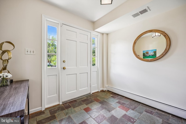 foyer with baseboard heating, stone tile flooring, and plenty of natural light