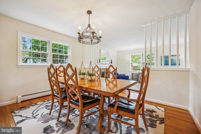 dining room with a chandelier, healthy amount of natural light, wood finished floors, and baseboards