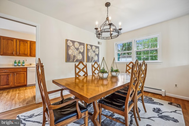 dining space featuring a chandelier, light wood-style floors, a baseboard heating unit, and baseboards
