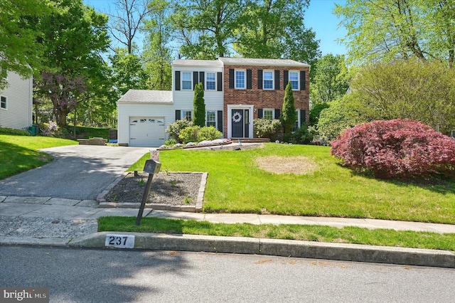 colonial house with a garage, a front lawn, and aphalt driveway