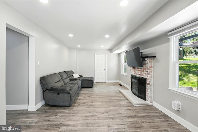 living room featuring a healthy amount of sunlight, a fireplace, recessed lighting, and wood finished floors