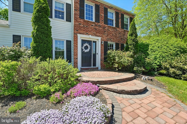 view of exterior entry featuring brick siding