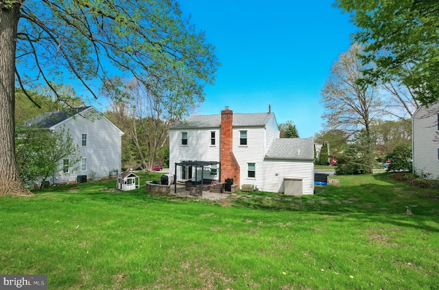 rear view of house with a yard, cooling unit, a chimney, and a patio area