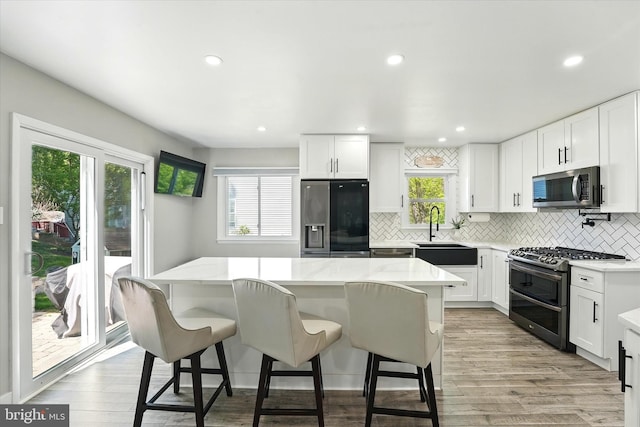 kitchen with decorative backsplash, a kitchen island, a sink, a wealth of natural light, and stainless steel appliances