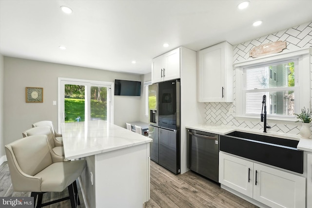 kitchen with backsplash, stainless steel dishwasher, a sink, fridge with ice dispenser, and white cabinets