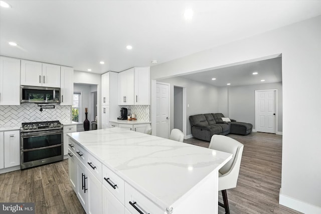 kitchen with appliances with stainless steel finishes, tasteful backsplash, baseboards, and dark wood finished floors