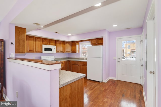 1129 Mediterranean Ave, Atlantic City, NJ 08401 - kitchen with brown cabinets, light countertops, a peninsula, light wood-style floors, and white appliances