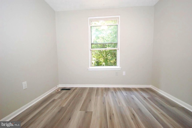 spare room featuring baseboards, wood finished floors, a healthy amount of sunlight, and visible vents