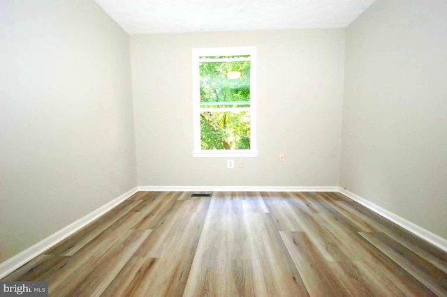 unfurnished room featuring baseboards, wood finished floors, and visible vents