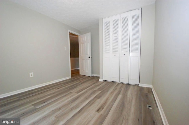 unfurnished bedroom with baseboards, wood finished floors, and a closet