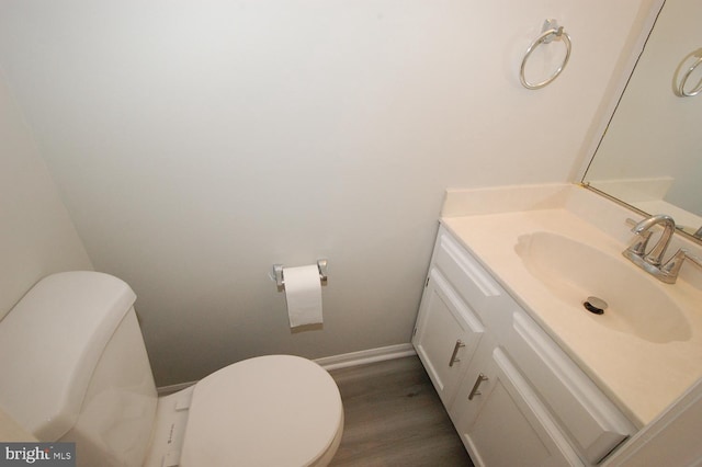 bathroom featuring vanity, baseboards, wood finished floors, and toilet