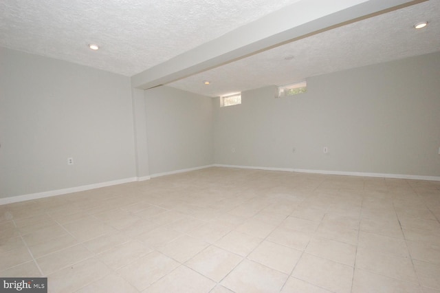 spare room with recessed lighting, a textured ceiling, light tile patterned floors, and baseboards